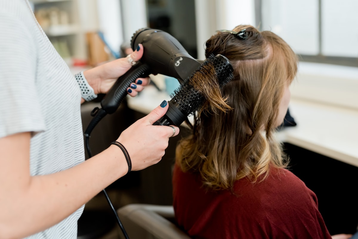 Kapster föhnt het haar van een klant in de salon